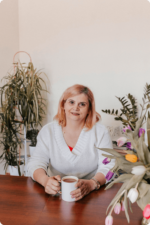 Coach Duszy Ela Rojek siedząca przy biurku wśród kwiatów.